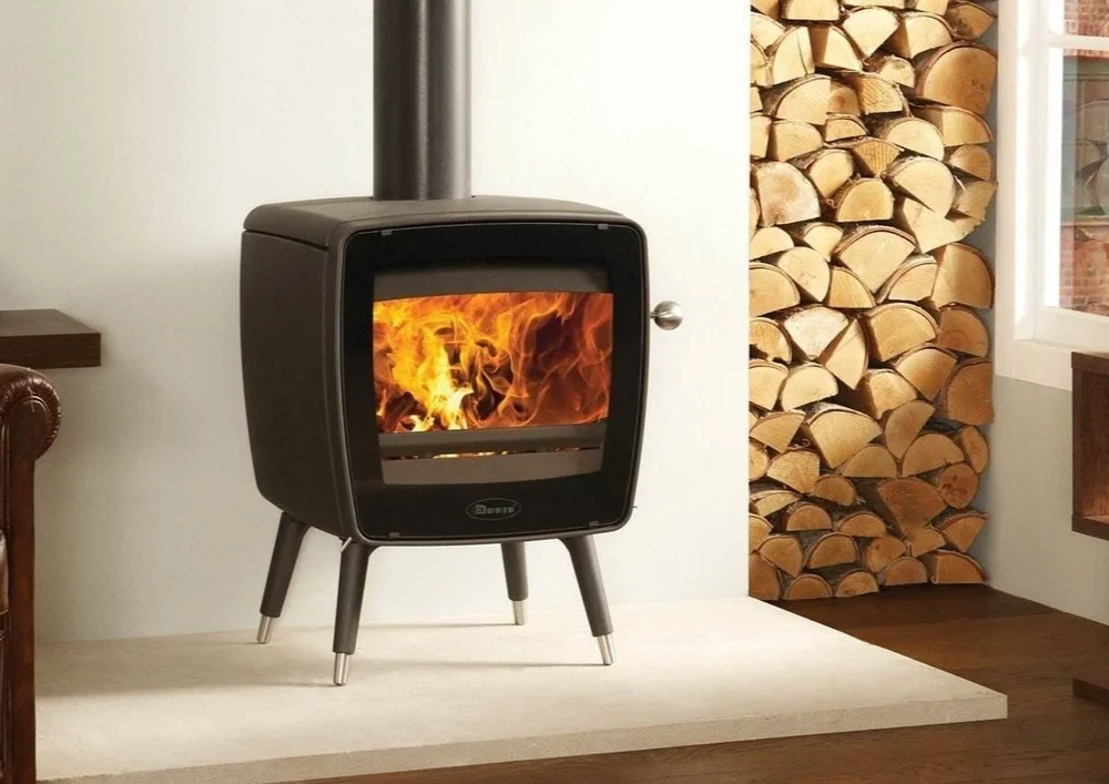 Freestanding black wood-burning stove beside a log store